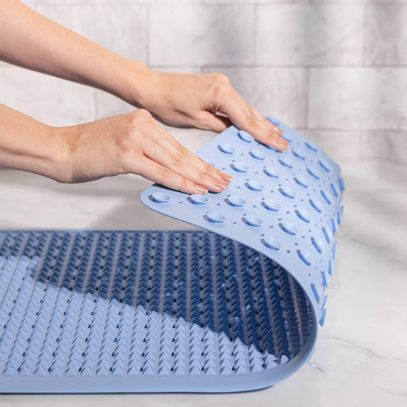 A person placing the blue PVRA acupressure mat in the shower